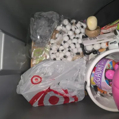 Sale Photo Thumbnail #132: A collection of holiday decor and trick-or-treat accessories contained in a grey storage tote. Includes a pink plastic pumpkin bucket, white plastic bucket, Easter egg hunt items, decorative mushrooms, novelty eyeball ping pong balls, felt bead garland, g