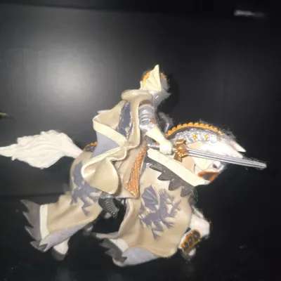 Sale Photo Thumbnail #23: Detailed plastic/PVC action figurine depicting a knight in full armor with a sword, riding a barded warhorse featuring dragon emblems. Appears to be in fair used condition with some minor lint/dust clinging to the surface and light wear to paint.