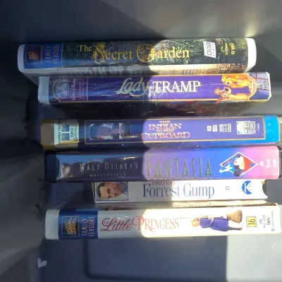 Sale Photo Thumbnail #116: Collection of VHS tapes featuring titles such as Walt Disney's Fantasia, Lady and the Tramp, The Secret Garden, The Indian in the Cupboard, A Little Princess, and Forrest Gump. Condition shows typical wear to cases and clamshells from storage and use.