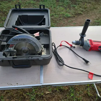 Sale Photo Thumbnail #160: Lot includes a corded Skilsaw Legend circular saw (2.4 HP, 11 Amps) housed in its original hard plastic carrying case, along with a corded Craftsman power drill featuring a removable side auxiliary handle and chuck key. Both tools show light signs of prev