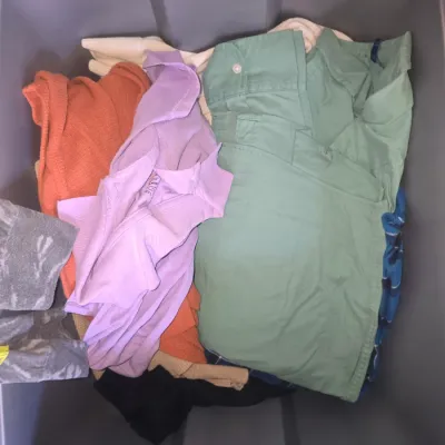 Sale Photo Thumbnail #129: Storage tote filled with an assortment of casual clothing including a Batman tie-dye graphic long-sleeve top, knits, sweaters, tops, and button-up shirts in various colors. Items show light wear consistent with gentle use.