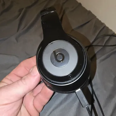Sale Photo Thumbnail #198: Pair of black Beats by Dre over-ear headphones with matching USB charging cable. Shows signs of wear, including scuffs and wear on the headband and ear pads. Untested.