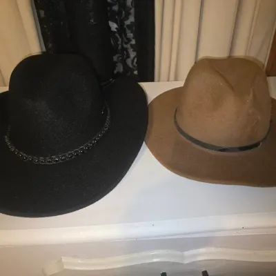 Sale Photo Thumbnail #96: Pair of wide-brim felt hats including one black western-style hat with a decorative beaded band and one tan/brown fedora style hat with a thin dark band. Both appear in good condition with minor signs of wear.