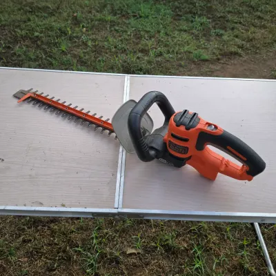 Sale Photo Thumbnail #164: Assortment of lawn and garden care tools. Includes a orange Black & Decker cordless leaf blower with charger, a pair of Fiskars hedge shears, and a pair of long-handled bypass loppers. All items show light to moderate signs of outdoor use. No battery