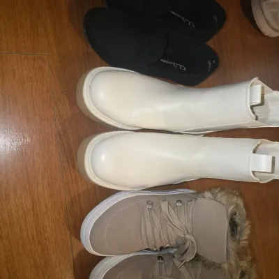 Sale Photo Thumbnail #38: A collection of 3 pairs of women's shoes and boots, including CL by Laundry black slip-on shoes, off-white Chelsea platform boots, and tan lace-up sneakers with faux fur trim. Shows light wear consistent with pre-owned condition.