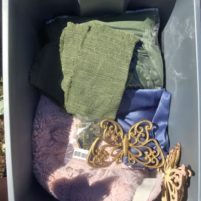 Sale Photo Thumbnail #122: Storage tote filled with an assortment of craft supplies, fabrics, and decor items. Includes a plastic storage tote, pink canvas bag/apron, faux fur fabric, green textured woven fabric, blue satin-like fabric, black/white woven textile, decorative butterf