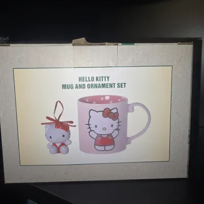 Sale Photo Thumbnail #20: Hello Kitty mug and holiday ornament gift set in original packaging. Features a pink polka dot interior mug with Hello Kitty graphic and a matching hanging ornament. Box shows minor shelf wear on the top tab.