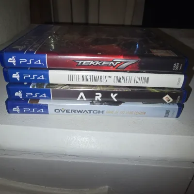 Sale Photo Thumbnail #62: Stack of 4 PlayStation 4 video game cases including:
- Tekken 7
- Little Nightmares Complete Edition
- Ark: Survival Evolved
- Overwatch: Game of the Year Edition

All items are in original cases. Cases show light shelf wear consistent with normal use. Di