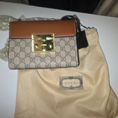 Sale Photo Thumbnail #86: Padlock GG Supreme canvas and brown leather shoulder bag featuring a gold-tone key lock closure and chain strap. Comes with a matching branded dust bag. Appears in new or very good condition with protective wrapping still attached.