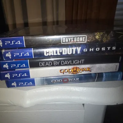 Sale Photo Thumbnail #65: A stack of 5 PlayStation 4 video game titles in original cases. Includes:
- Days Gone (factory sealed in plastic wrap)
- Call of Duty: Ghosts
- Dead by Daylight
- God of War III Remastered
- God of War

Condition: Cases show minor shelf wear. 'Days Gone' 