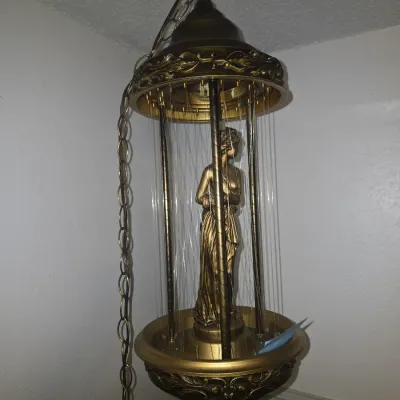 Sale Photo Thumbnail #16: Vintage Hollywood Regency style hanging oil rain lamp featuring a central classical goddess figure surrounded by rain strands. Metallic gold-tone finish with ornate scrollwork detailing on the top and bottom rims. Includes hanging chain and power cord. Un