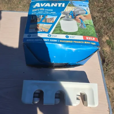 Sale Photo Thumbnail #144: Includes an Avanti AV-100 handheld HVLP paint and stain sprayer in its original packaging (box shows wear/denting) along with a white wall-mounted tool or mop/broom holder organizer. Items show light cosmetic wear; completeness of sprayer inside box is un