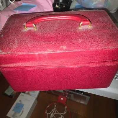 Sale Photo Thumbnail #49: Vintage red textured train case/jewelry box with handle and top carry latch, showing moderate surface wear and dust. Interior includes three packages of new iron-on embroidered patches (playing cards, stars, lettering) and a houndstooth fabric headband wi