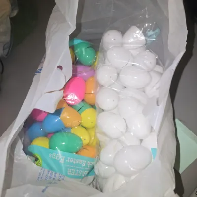 Sale Photo Thumbnail #76: A collection of plastic fillable Easter eggs in a shopping bag, featuring a bag of solid white eggs and a bag of multi-colored eggs (pink, blue, yellow, green, orange). Appears to be in good, unused or lightly used condition.