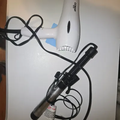 Sale Photo Thumbnail #67: Pair of hair styling tools including a white Conair 1875 watt hair dryer and a metallic curling iron with a black handle. Items show signs of light use and wear. Plugs and power cords attached.