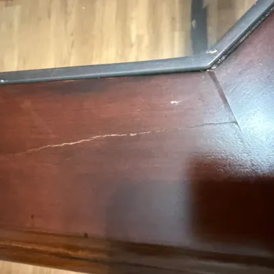 Sale Photo Thumbnail #29: Close-up detail of a dark wood table frame with glass top insert, showing visible finish scratches and surface wear.