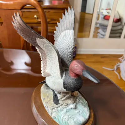 Sale Photo Thumbnail #283: Hand-painted duck figurine depicting a canvasback in flight, mounted on an oval wooden display base.