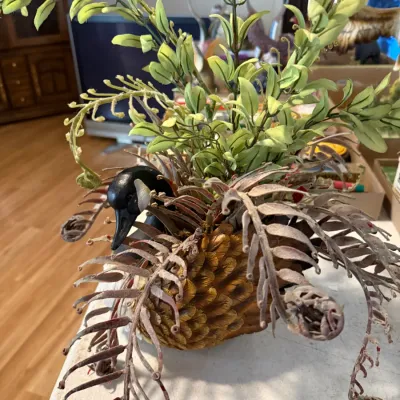 Sale Photo Thumbnail #227: Decorative goose figurine planter adorned with artificial foliage and faux fern fronds.