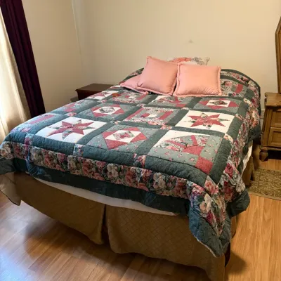 Sale Photo Thumbnail #114: Traditional patchwork quilt with star and floral motifs, paired with pink throw pillows and a neutral bed skirt.