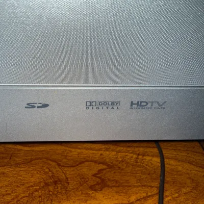 Sale Photo Thumbnail #92: Close-up of a silver-finish television speaker mesh featuring SD card, Dolby Digital, and HDTV integrated tuner logos.