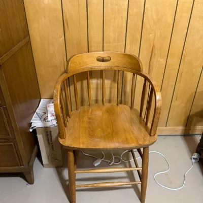 Sale Photo Thumbnail #382: Vintage light oak captain's chair featuring a spindle back, curved armrests, and a cutout handhold on the top rail.