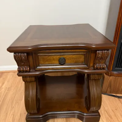 Sale Photo Thumbnail #15: Traditional dark wood end table featuring carved acanthus leaf accents, a single drawer with a medallion knob, and a lower open shelf.