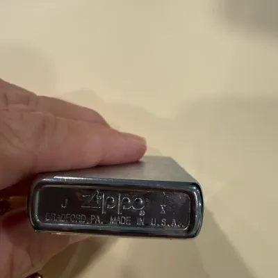 Sale Photo Thumbnail #419: Bottom stamp of a chrome Zippo pocket lighter, date-coded J X indicating manufacture in October 1994.