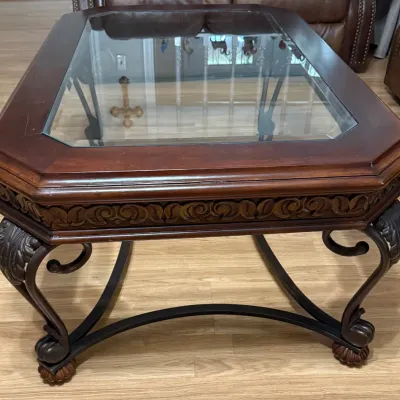 Sale Photo Thumbnail #30: Traditional wooden coffee table featuring a glass insert top, carved relief apron, and ornamental metal scroll legs with carved feet.