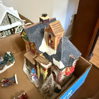 Sale Photo Thumbnail #357: Hand-painted miniature Christmas village house featuring snow-covered roofs, a snowman figurine, and festive accents.