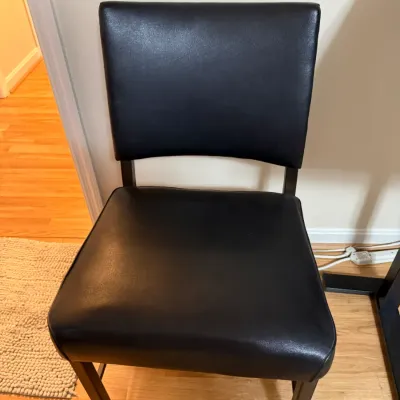Sale Photo Thumbnail #375: Contemporary dining chair featuring black faux leather upholstery and dark wooden legs.