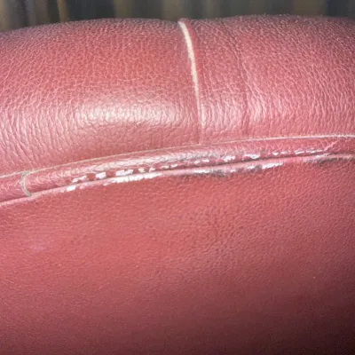 Sale Photo Thumbnail #69: Close-up detail of burgundy leather upholstery, showing minor surface wear along a piped seam.