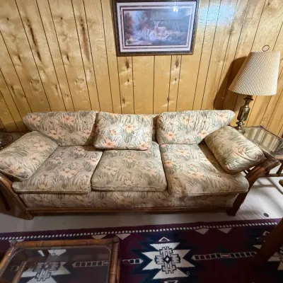 Sale Photo Thumbnail #401: Vintage rattan sofa with floral upholstery, flanked by matching glass-top end tables with brass lamps.