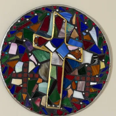 Sale Photo Thumbnail #48: Round stained-glass mosaic wall plaque featuring a gold-bordered cross emblem surrounded by colorful tesserae.