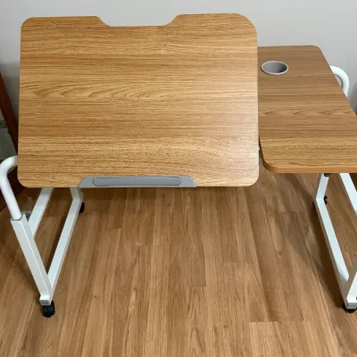 Sale Photo Thumbnail #26: Modern adjustable rolling overbed desk with a wood grain laminate top, tilting main surface, cup holder, and white metal frame.