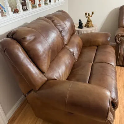 Sale Photo Thumbnail #10: Contemporary brown leather reclining loveseat featuring plush pillow-top cushioning and subtle nailhead trim along the base.