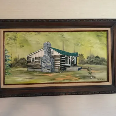 Sale Photo Thumbnail #223: Framed landscape painting depicting a rustic log cabin with a stone chimney, signed by artist Ken Holland in the lower right corner.
