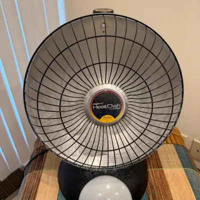 Sale Photo Thumbnail #143: Presto HeatDish Plus Footlight parabolic electric space heater, featuring a round metallic dish reflector and black safety grill.