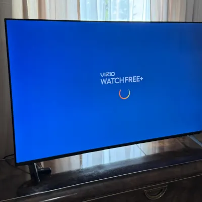 Sale Photo Thumbnail #100: Modern Vizio smart flat-screen television powered on and resting on a dark wooden cabinet.