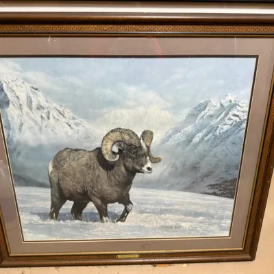 Sale Photo Thumbnail #391: Framed wildlife art print depicting a bighorn sheep in a snowy mountain landscape, presented in a layered wood frame with a double mat.