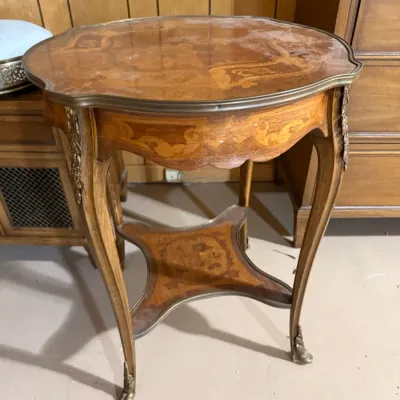 Sale Photo Thumbnail #385: French Provincial style marquetry accent table featuring intricate wood inlay, brass trim, cabriole legs, and a lower tier shelf.