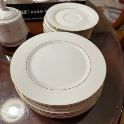 Sale Photo Thumbnail #301: Set of white fine china dinnerware with gold rim detailing, including plates, saucers, teacups, and a covered sugar bowl.