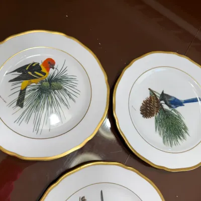 Sale Photo Thumbnail #215: Set of vintage Ray Harm collector plates featuring detailed bird and pine branch illustrations with gold rims.
