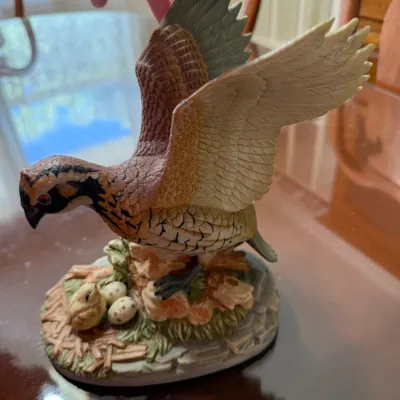 Sale Photo Thumbnail #255: Hand-painted porcelain bird figurine depicting a bobwhite quail in flight above a nest with a chick and eggs.
