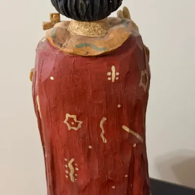 Sale Photo Thumbnail #46: Rear view of a hand-carved and hand-painted wooden Santo figure featuring a crown, a painted red cape with gilded details, and a pedestal base.