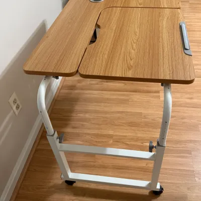 Sale Photo Thumbnail #25: Modern adjustable rolling desk with light wood-grain tops, cup holder, tilt function, and white metal frame.