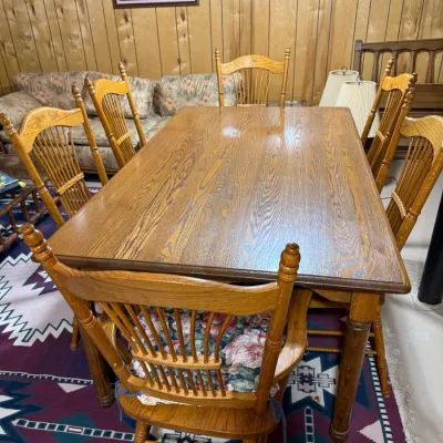 Sale Photo Thumbnail #408: Traditional golden oak dining table set with six spindle-back chairs, set over a Southwestern-style area rug.