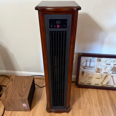 Sale Photo Thumbnail #147: Tall electric tower heater in a cherry wood cabinet with digital control display, flanked by a small woodgrain heater and a nautical shadow box frame.