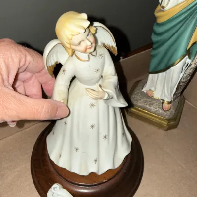 Sale Photo Thumbnail #274: Vintage porcelain angel figurine on a round wooden base, with gold star accents on her gown, appearing to have a minor repair at the hand.