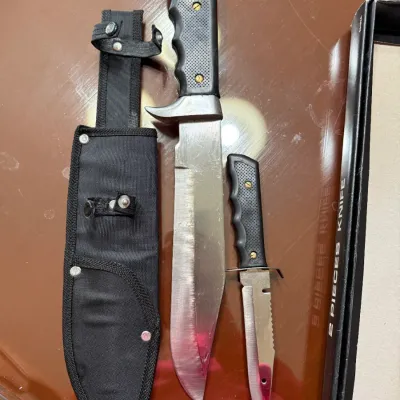 Sale Photo Thumbnail #267: Two-piece tactical knife set featuring a large bowie knife and a smaller companion knife, both with textured black handles and a black nylon sheath.