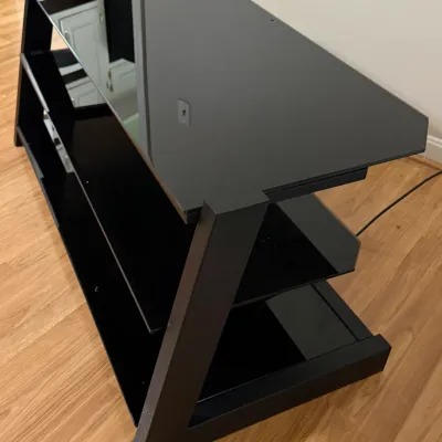 Sale Photo Thumbnail #33: Modern black glass and metal TV stand featuring a three-tier design with angled side supports.